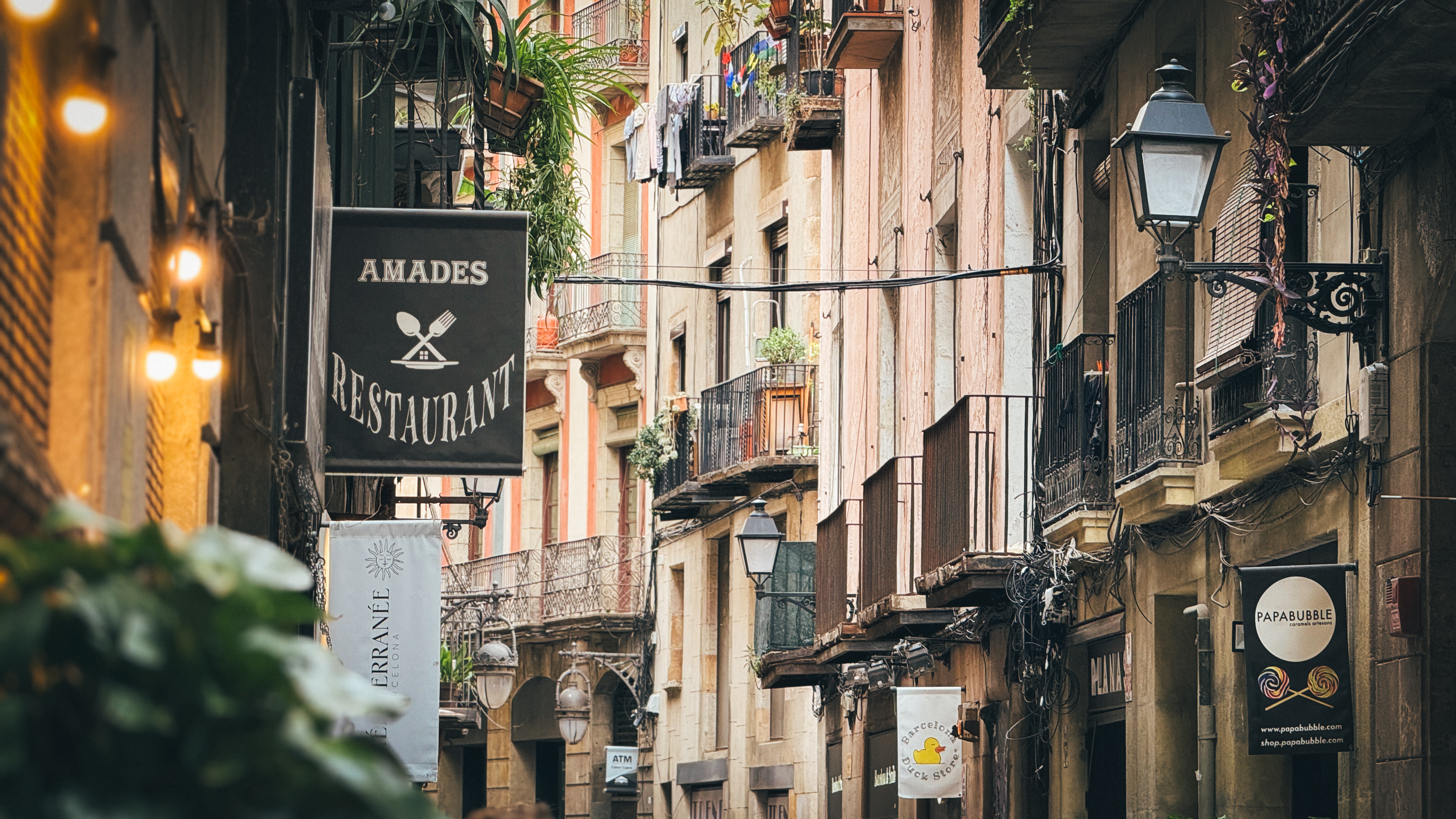 A narrow lane in Barcelona's old city with restaurants and evening lights