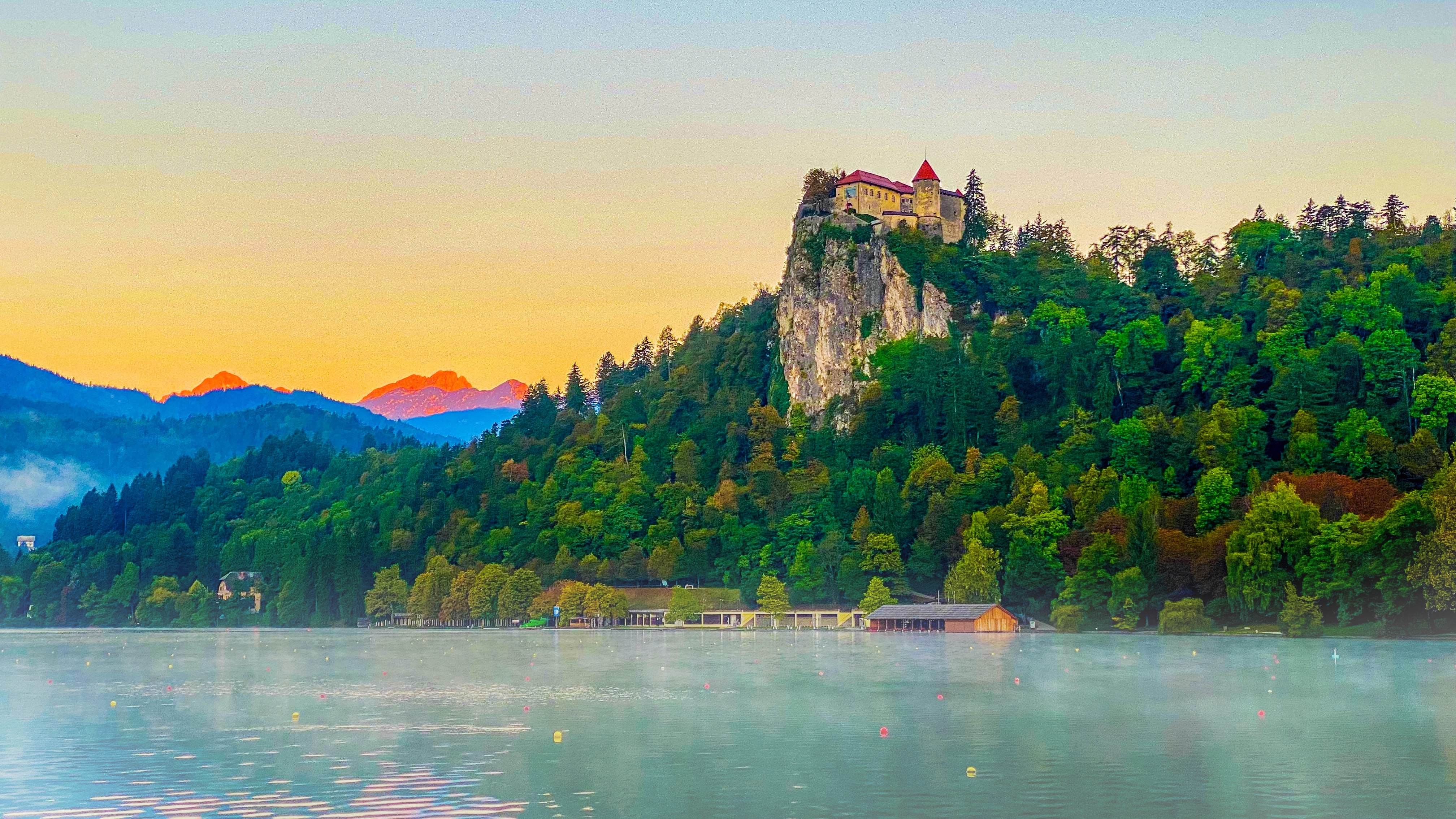 Iconic Lake Bled view from Mala Osojnica viewpoint - breathtaking panorama of the lake with the island church, mist rising from the water, and mountain peaks in the background